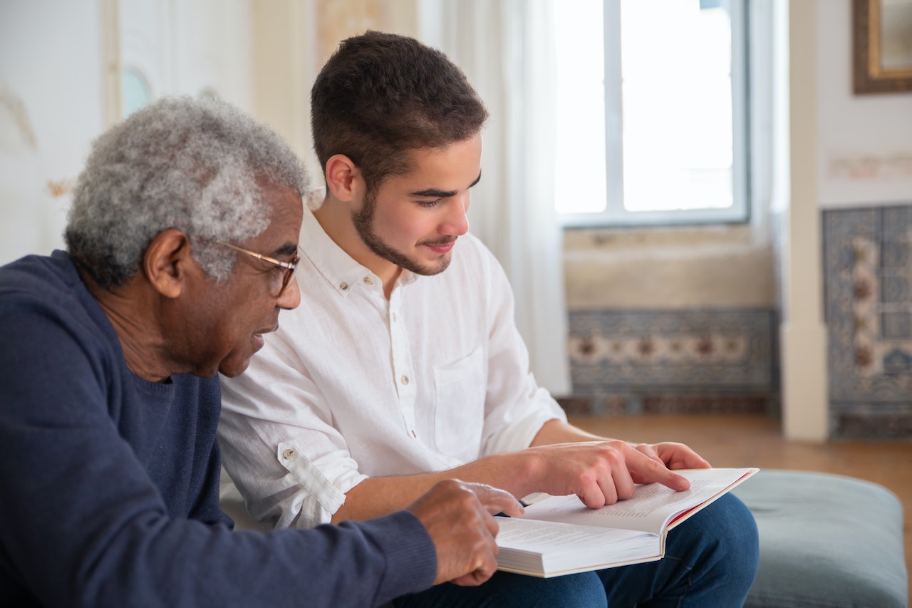 man reading a book with elder in nursing home