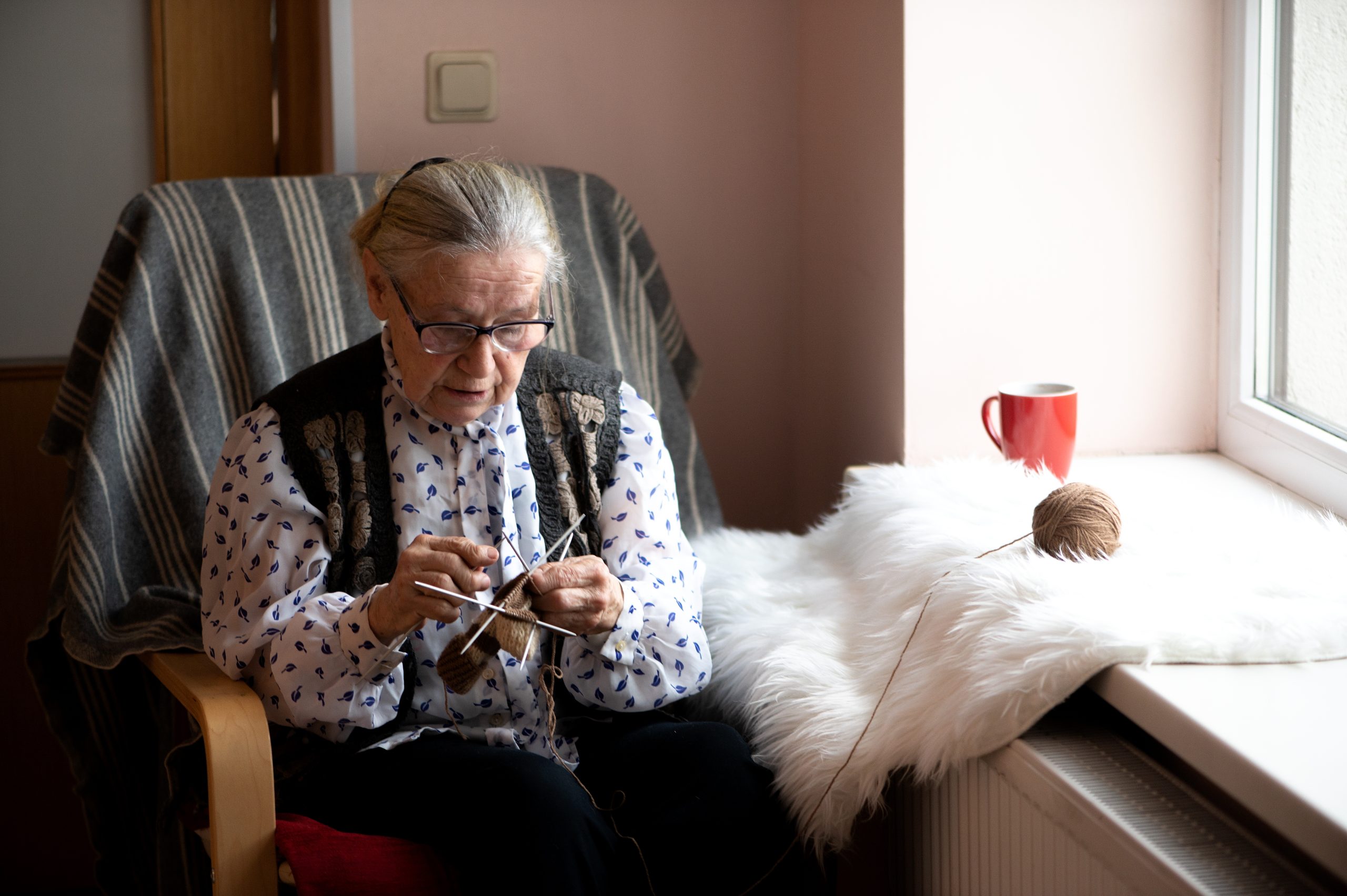 old woman knitting in a nursing home by the window