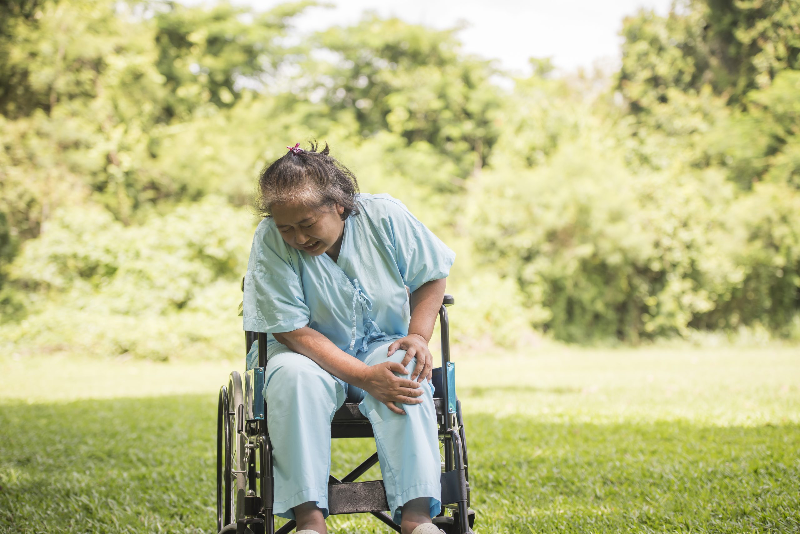 Elderly woman sitting on wheelchairs with knee pain