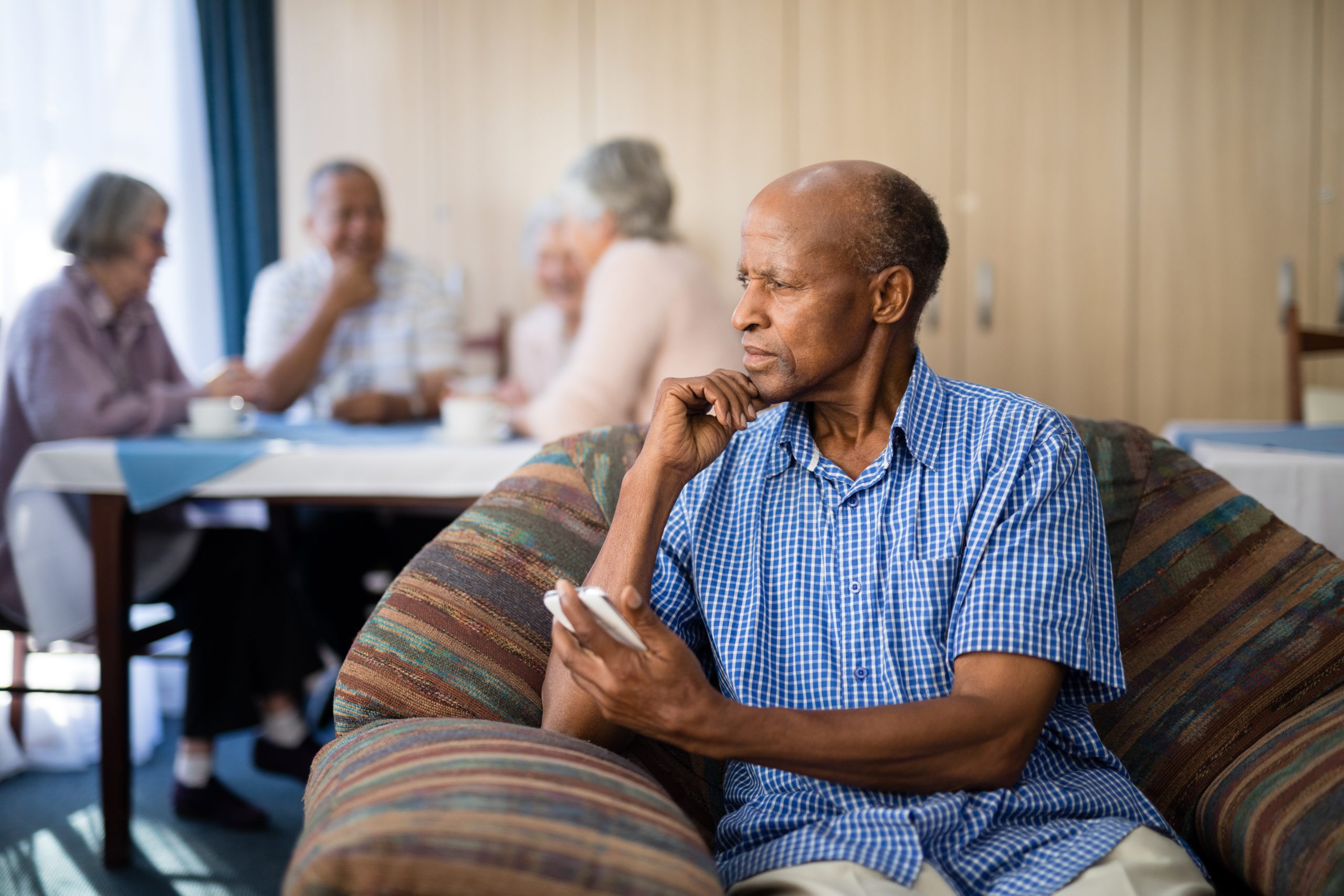 Thoughtful senior man holding mobile phone